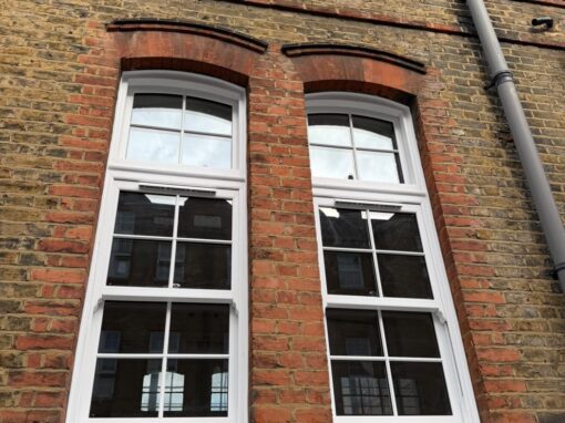 The two tall arched windows after the works, with new white frames and a repainted sill