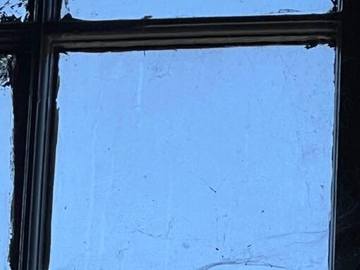 Close up of a rotten window frame, peeling paint, cracked pane