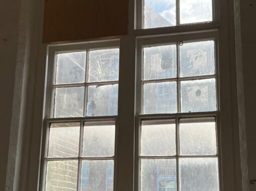 Window from inside, plywood panel boarded in, grimy glass