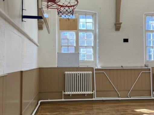 Sports hall, plywood panel boarded into the upper window
