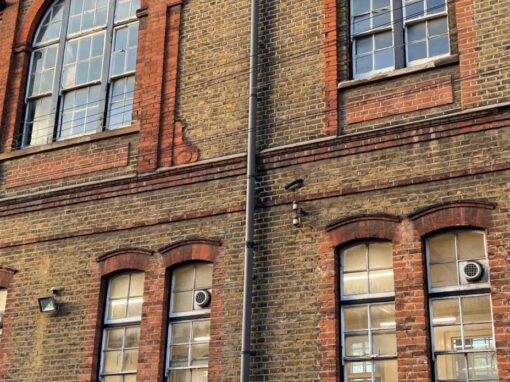 The arched gable window and adjoining bay before the works, with the original dark-framed windows